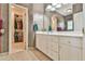 Bathroom featuring a vanity, mirror, and an open doorway to a walk-in closet filled with clothes at 2644 Nutwood Trce, Duluth, GA 30097