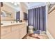 Bright bathroom features a single vanity, shower with blue curtain, and neutral color scheme at 2644 Nutwood Trce, Duluth, GA 30097