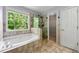 Bright bathroom featuring a soaking tub, glass-enclosed shower, and natural light at 7260 Foxberry Ct, Cumming, GA 30041