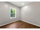 Bright bedroom featuring wood-look flooring and a window overlooking lush greenery at 7260 Foxberry Ct, Cumming, GA 30041