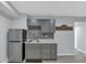 Modern basement kitchenette featuring gray cabinets, tile backsplash, and stainless steel refrigerator at 151 Mark Se Ln, Smyrna, GA 30082
