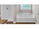 Bathroom features a soaking tub beneath a window and a separate shower stall, all with modern fixtures at 151 Mark Se Ln, Smyrna, GA 30082