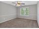 A well-lit bedroom featuring neutral carpeting, a ceiling fan, and a window with views of trees at 151 Mark Se Ln, Smyrna, GA 30082