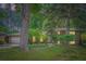 Brick home exterior, illuminated by landscape lighting with mature trees and lush green lawn at 2687 Goodfellows Rd, Tucker, GA 30084