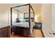 A bedroom with a four-poster bed, dark hardwood floors, and a stylish nightstand is bathed in natural light at 532 Pelham Pl, Mcdonough, GA 30253