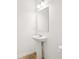 Modern powder room featuring a pedestal sink, framed mirror, and wood flooring at 5383 Heron Bay Blvd, Locust Grove, GA 30248