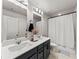 Bathroom with dual sinks, vanity with dark cabinets and a bathtub-shower with curtain at 4065 Holland Grove Rd, Lawrenceville, GA 30044