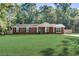 Charming red brick home with a well-manicured front yard and mature trees in the background at 715 Cowan Rd, Covington, GA 30016