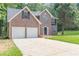 Two-story brick home featuring an attached two-car garage, dark shutters, and a lush green lawn at 99 Ashtonbrook Dr, Mcdonough, GA 30252