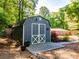 Backyard shed featuring double doors with white trim and mature landscaping at 3290 Custer Lake Nw Dr, Marietta, GA 30064