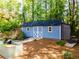 Charming blue storage shed with white trim and double doors surrounded by lush landscaping and a galvanized planter at 3290 Custer Lake Nw Dr, Marietta, GA 30064