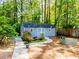 Blue storage shed with white trim and double doors surrounded by lush landscaping and a galvanized planter at 3290 Custer Lake Nw Dr, Marietta, GA 30064