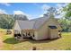 Back exterior view of house with large yard, covered patio with seating and mature trees at 104 Federal Path, Temple, GA 30179