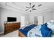 Cozy main bedroom with tray ceilings, a wooden bed frame, a dresser with a television, and a crib at 104 Federal Path, Temple, GA 30179