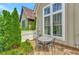 Cozy patio area with stone flooring, a round table, and chairs, surrounded by lush greenery and a charming fence at 11189 Serenbe Ln, Chattahoochee Hills, GA 30268