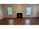 Bright living room featuring wood-look floors, a fireplace, and natural light from two windows, creating a cozy atmosphere at 1780 Spring Hill Cv, Lithonia, GA 30058