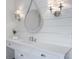 Bright bathroom with white vanity, stone countertops, decorative mirror, sconces, and wood plank walls at 210 Tifton Ln, Roswell, GA 30075