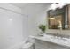 Bathroom with tub and shower combo, granite countertop, gray cabinets, mirror, and green plant at 210 Tifton Ln, Roswell, GA 30075