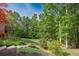 Backyard with a small retaining wall, green grass, landscaping and a backdrop of dense trees at 313 Red Fox Dr, Canton, GA 30114