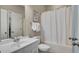 Bright bathroom with a white sink, toilet, tub with shower curtain, and artwork on the wall at 313 Red Fox Dr, Canton, GA 30114