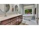 Bathroom with double sinks, wood cabinets, a bathtub, and natural lighting from the window at 313 Red Fox Dr, Canton, GA 30114
