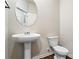 Clean powder room with pedestal sink, round mirror, and modern toilet at 3573 Stonebranch Ln, Loganville, GA 30052