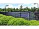Fenced in tennis courts with the Woodlands logo on the windscreen and trimmed hedges in the foreground at 111 Churchcliff Dr, Woodstock, GA 30188