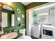 Green bathroom featuring toilet, sink, mirror, decor and a laundry room with washer and dryer at 115 N Loblolly Xing, Temple, GA 30179