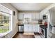 Bright kitchen featuring a window over the sink, white cabinets, stainless steel appliances, and hardwood floors at 115 N Loblolly Xing, Temple, GA 30179