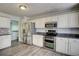 Kitchen showcases white cabinetry, stainless steel appliances, and a view to the staircase at 4199 Wyndham Park Way, Buford, GA 30519