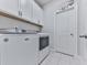 Functional laundry room with white appliances, cabinets, and white tile flooring at 132 Neese Farm Dr, Woodstock, GA 30188