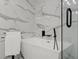 Modern bathroom features a sleek white bathtub with stylish fixtures and elegant marble-patterned tile at 2120 Pair Sw Rd, Marietta, GA 30008