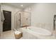 Bright bathroom features a luxurious soaking tub with stone surround and tiled shower at 719 Hammond Dr, Woodstock, GA 30188