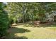 Expansive backyard featuring mature trees, a green lawn, and a wooden fence at 737 Dushea Nw Ct, Kennesaw, GA 30144