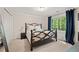 Comfortable bedroom with a decorative metal bed frame, closet, and sunny window with blue curtains at 1819 Walker Ridge Sw Dr, Marietta, GA 30064