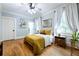 Bright bedroom with hardwood floors, a cozy bed, two windows with white curtains, and light blue walls at 132 Olympic Pl, Decatur, GA 30030