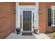 Close-up of a classic black front door with sidelights, elegant lighting fixtures, and potted plants at 4044 Kenway Se Pl, Smyrna, GA 30082