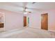 Spacious pink bedroom featuring carpeted floors, ceiling fan, and two entry doors at 502 Knollwood Pl, Woodstock, GA 30188