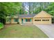 Charming yellow ranch-style home with a two-car garage, a manicured lawn and trees in the background at 502 Knollwood Pl, Woodstock, GA 30188