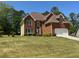Inviting brick home with a two-car garage and a spacious, green front lawn at 2246 Carrington Dr, Ellenwood, GA 30294