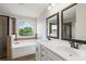 A bathroom with double vanities, framed mirrors, large window, soaking tub, and tiled shower at 3625 New River Ct, Cumming, GA 30040