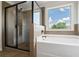 Elegant bathroom with a glass-enclosed shower, a soaking tub under a large window, and earth tone tiles at 3625 New River Ct, Cumming, GA 30040