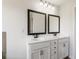 Bathroom featuring double vanities with white cabinets, two ornate mirrors, and modern lighting at 3625 New River Ct, Cumming, GA 30040