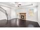 Bright living room with dark hardwood floors, stone fireplace, and open staircase to second floor at 5749 Creek Indian Dr, Sugar Hill, GA 30518