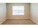 Empty bedroom with beige walls, carpet flooring, and natural light streaming through the window at 4205 Post Oak Grv, Atlanta, GA 30349