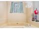 Relaxing bathroom featuring a beige-tile enclosed tub, with a window view and cute lighthouse decor at 127 Stagecoach Trl, Stockbridge, GA 30281