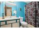 Vibrant blue bathroom with a single vanity, a commode, and a shower/tub combo with a patterned curtain at 127 Stagecoach Trl, Stockbridge, GA 30281