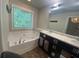 Bright bathroom features a soaking tub under a window and a double sink vanity with decorative accents at 236 Bobbie Way, Woodstock, GA 30189