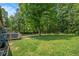 Spacious backyard featuring lush green grass, mature trees, and a wooden deck at 6450 Ivey Se Rd, Mableton, GA 30126