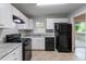 Clean kitchen featuring sleek black appliances, white cabinets, and a view to the outdoor deck at 5340 The Savoy St, Atlanta, GA 30349